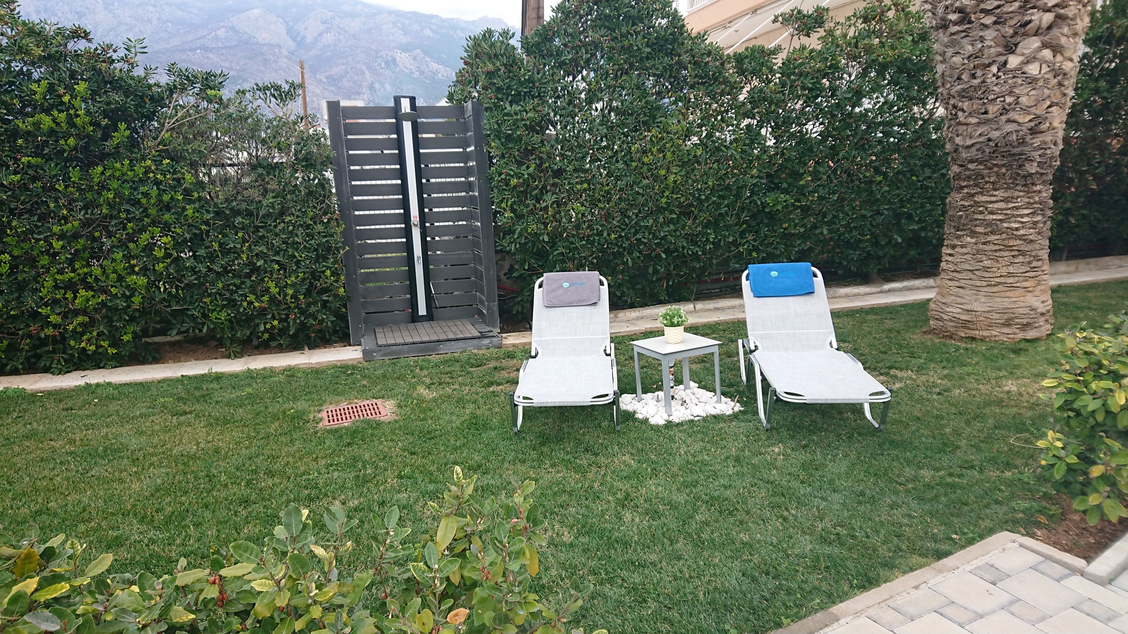 Dos sillones de exterior con una mesita y una maceta, frente a un fondo de vegetación exuberante y una vista a la montaña.