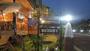 A wooden building with a 'welcome' sign, a bicycle, and a small garden with decorative animals. - Phupha Inn Resort (Wang Thong)