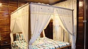 A four-poster canopy bed with a floral bedspread, wooden headboard, and a bedside table with a lamp. - Phupha Inn Resort (Wang Thong)