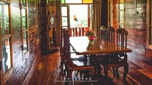 A traditional wooden interior with a dining table and chairs, large windows, and a view of the outdoors. - Phupha Inn Resort (Wang Thong)