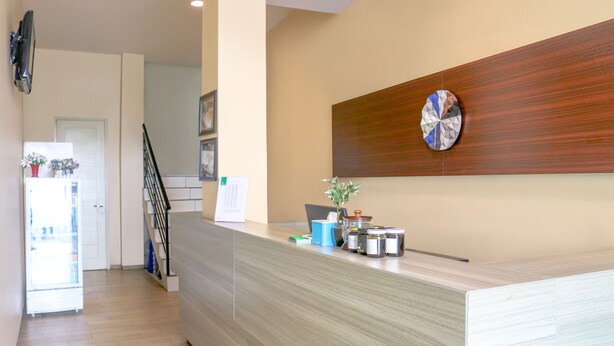 Zona de recepción con un mostrador de madera, una pieza decorativa en la pared y una escalera que lleva a otra habitación.