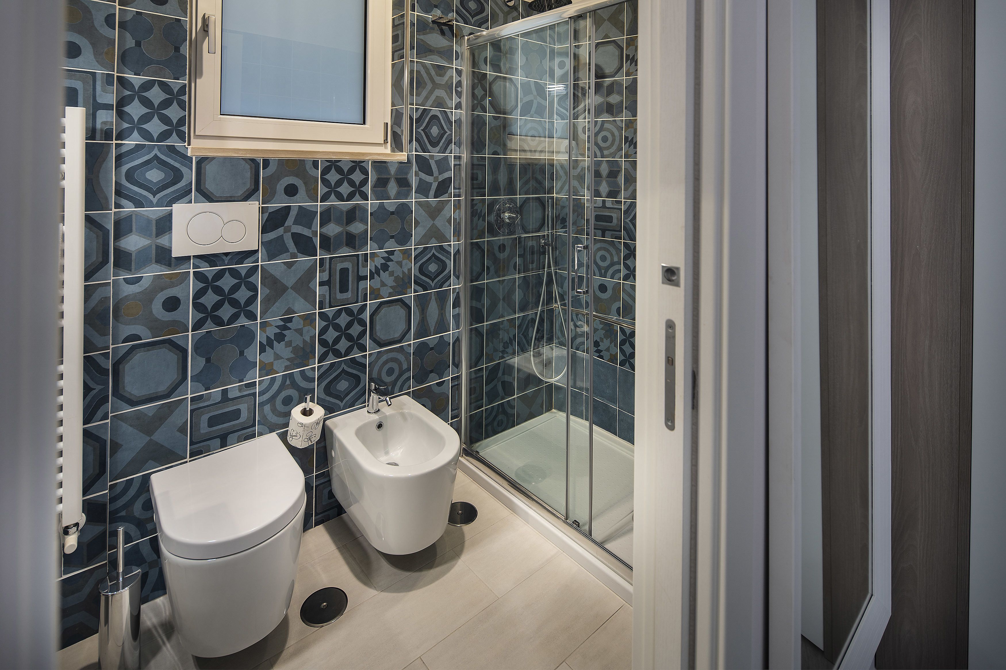 A modern bathroom with a toilet, bidet, and glass shower enclosure.