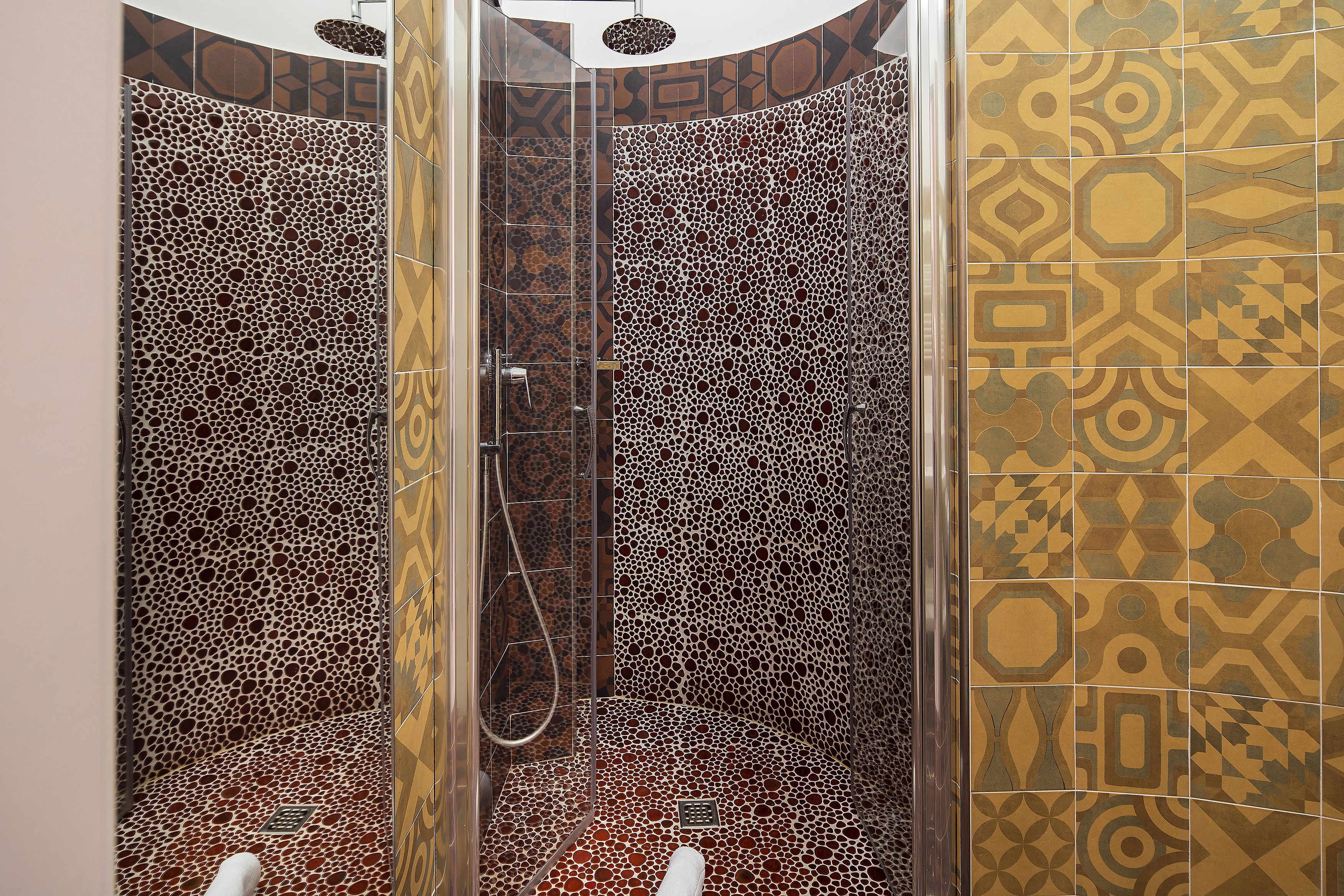 A shower with a unique mosaic tile design.