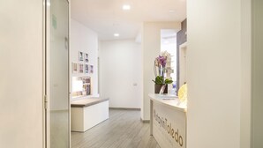 Un espace d’accueil comprenant un comptoir de réception, une plante et des tableaux encadrés accrochés au mur.