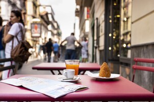 Een tafel met een menukaart, een glas sinaasappelsap en een croissant.