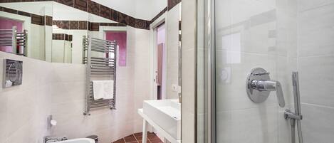 A modern bathroom with a glass-enclosed shower, a white sink, and a mirror with a geometric tile border.