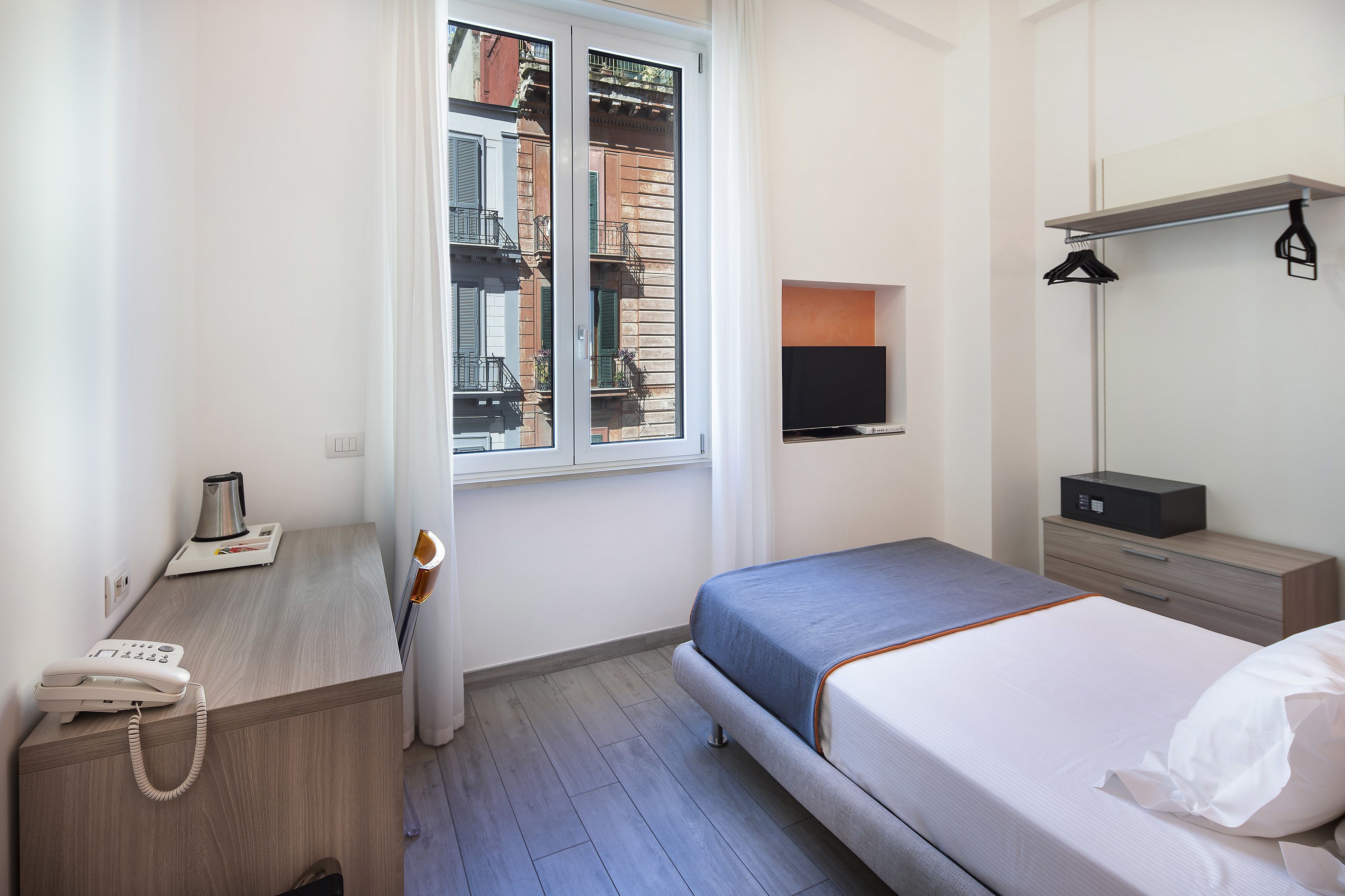 Une chambre d’hôtel comprenant un lit, un bureau avec un téléphone, une télévision et une armoire.