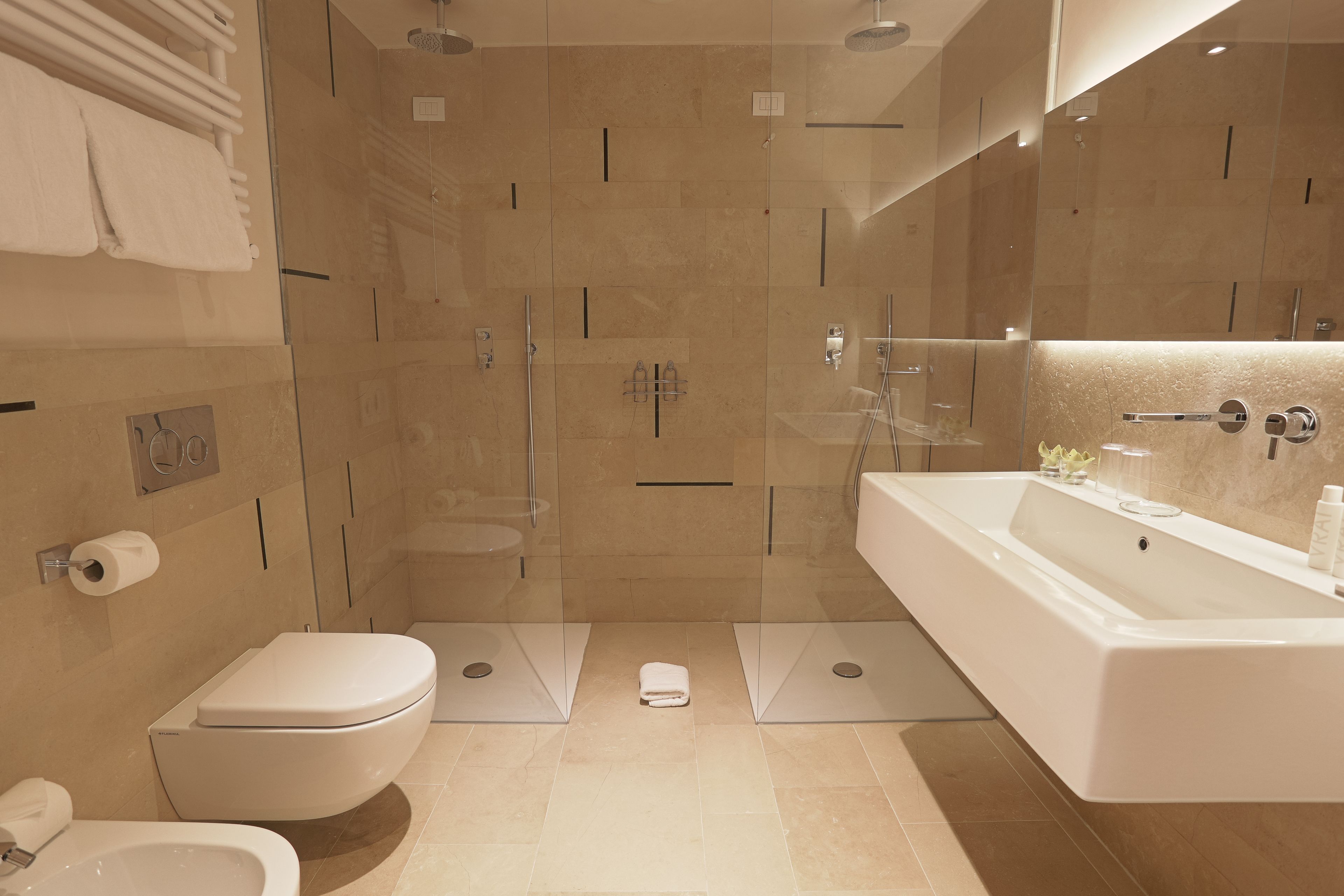Un baño moderno con inodoro, bidé y cabina de ducha con mampara de vidrio.