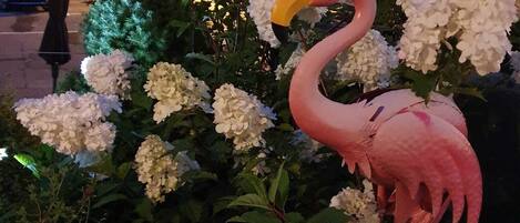 Una escultura de flamenco rosa entre flores blancas, de noche.
