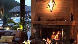 A cozy room with a fireplace, wooden furniture, and a view of the outside.