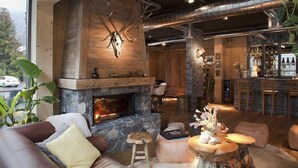A cozy interior with a stone fireplace, wooden beams, and a bar area.