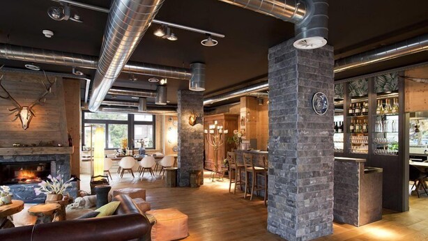 A spacious lounge area with a stone fireplace, wooden furniture, and a bar area with shelves of bottles.