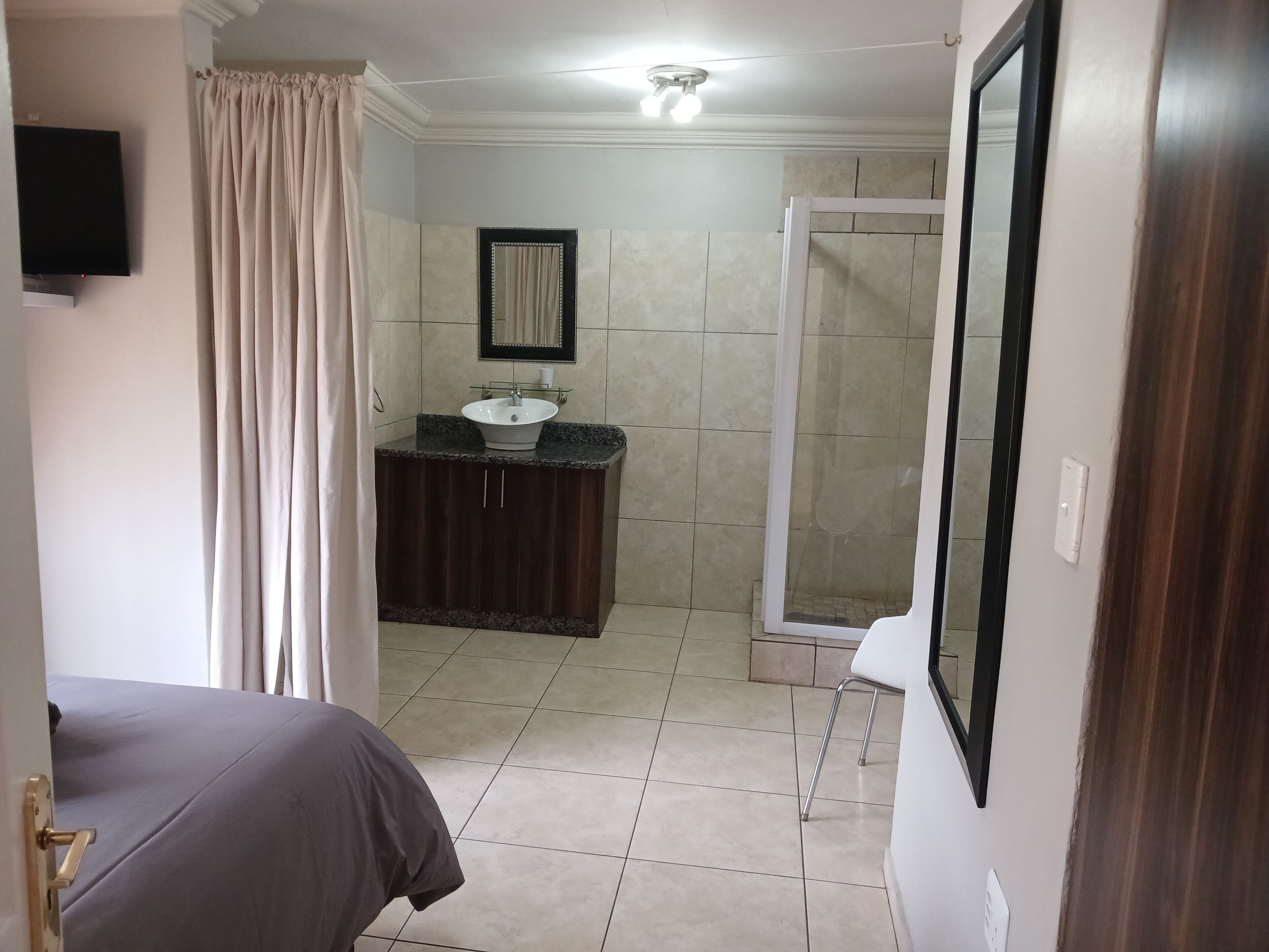 Un baño con lavamanos, espejo, ducha e inodoro.