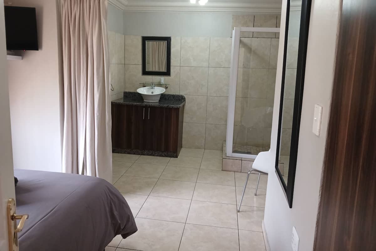 A bathroom with a sink, mirror, shower, and toilet.