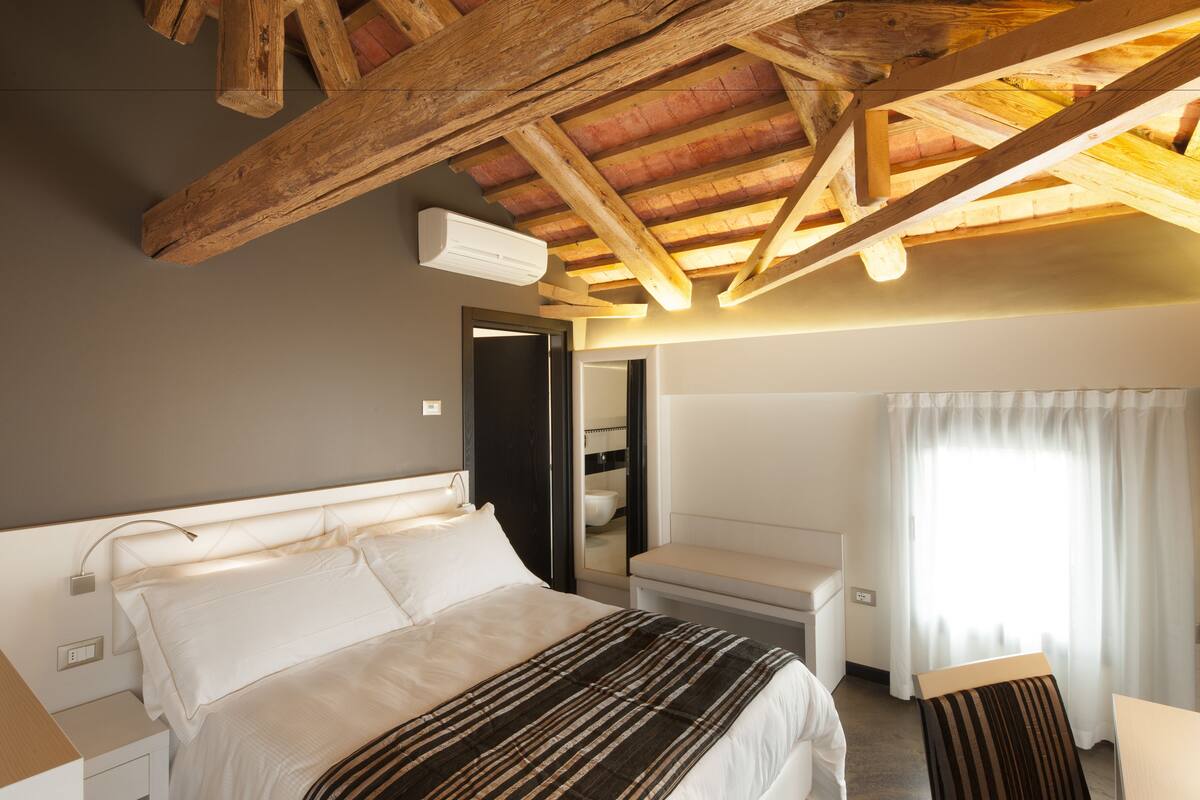 A bedroom with a bed, bedside table, and a wooden ceiling structure.