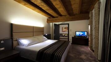Un dormitorio con una cama, televisión, mesita de noche y pared de ladrillo.