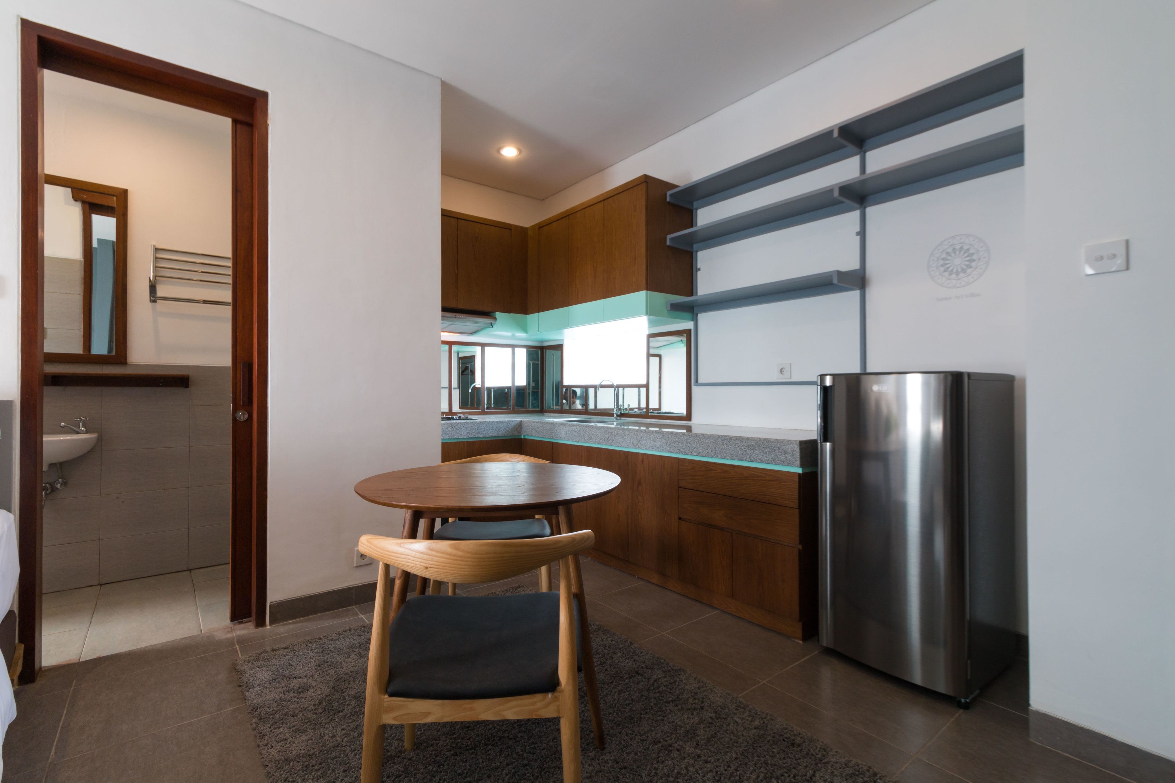 A modern kitchen with a stainless steel refrigerator, wooden cabinets, and a dining area with a table and chairs.