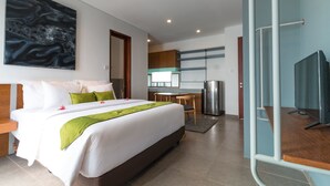 Una habitación de hotel moderna con una cama grande, un escritorio, una kitchenette y un televisor.