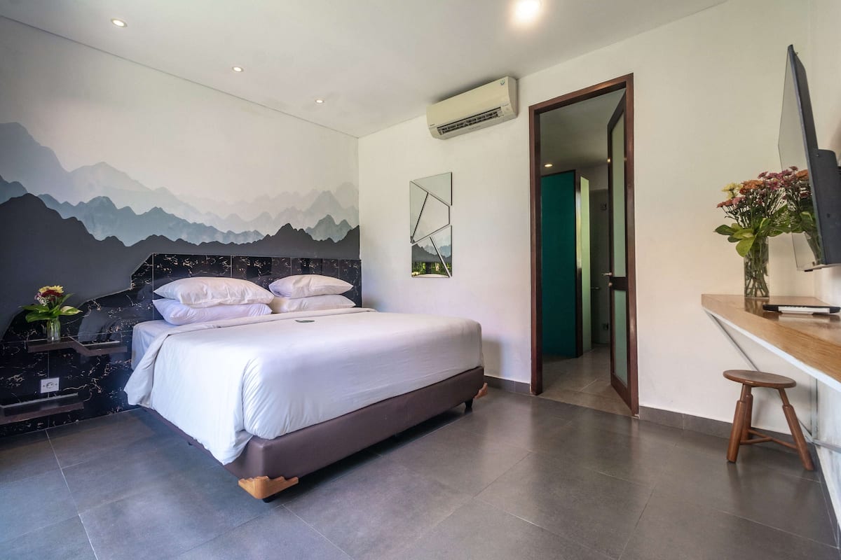 Un dormitorio moderno con una cama, un escritorio y un televisor.