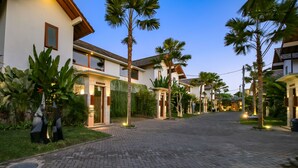 Una calle residencial con casas, palmeras y una calzada pavimentada.