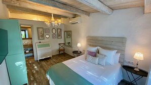 Quarto com uma cama grande, teto de madeira, espelho e cômoda.