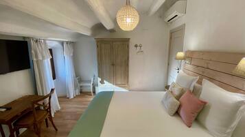 Un dormitorio con cama, mesita de noche, silla y lámpara colgante.