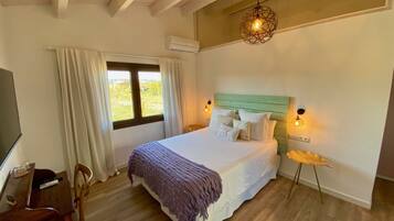 A bedroom with a bed, a desk, a chair, a window with curtains, and a hanging light fixture.
