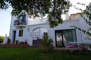 A white building with a balcony, a door, and a window. There is a table and chairs outside. - B&B Wine and Cooking Penedès (El Pla del Penedes)