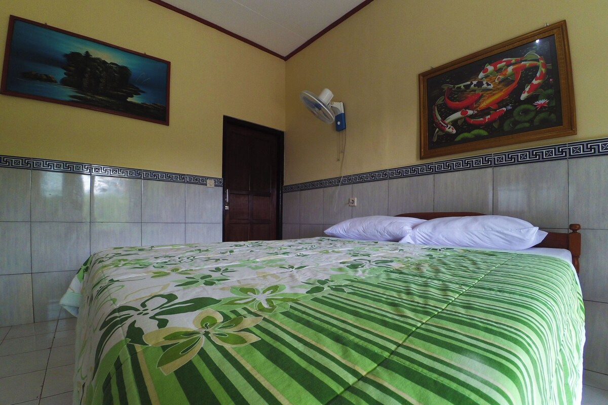 Una habitación de hotel con una cama, una puerta y dos cuadros en las paredes.
