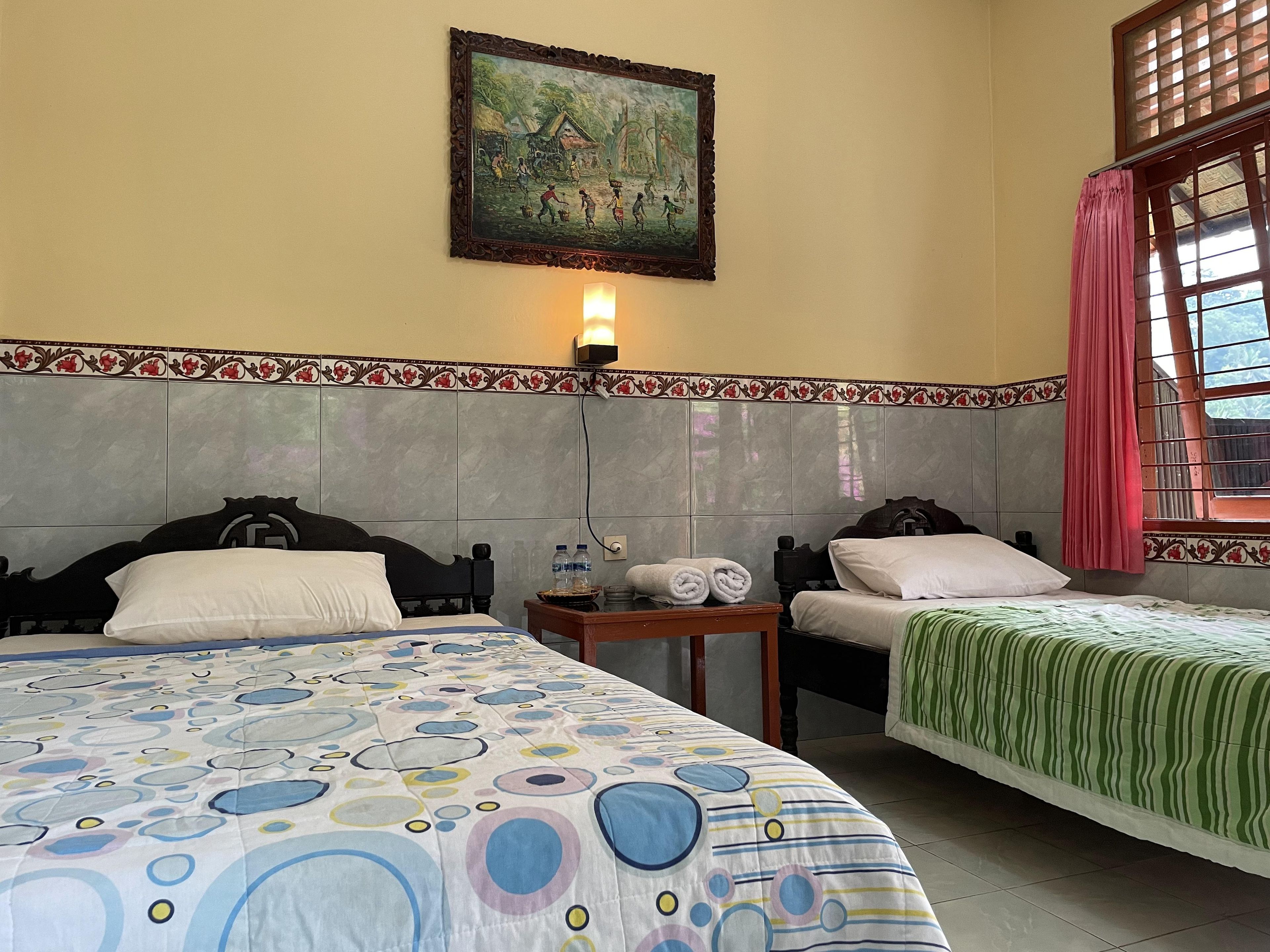 Habitación de hotel con dos camas, un cuadro en la pared, una ventana con cortinas y un cabecero de azulejos.