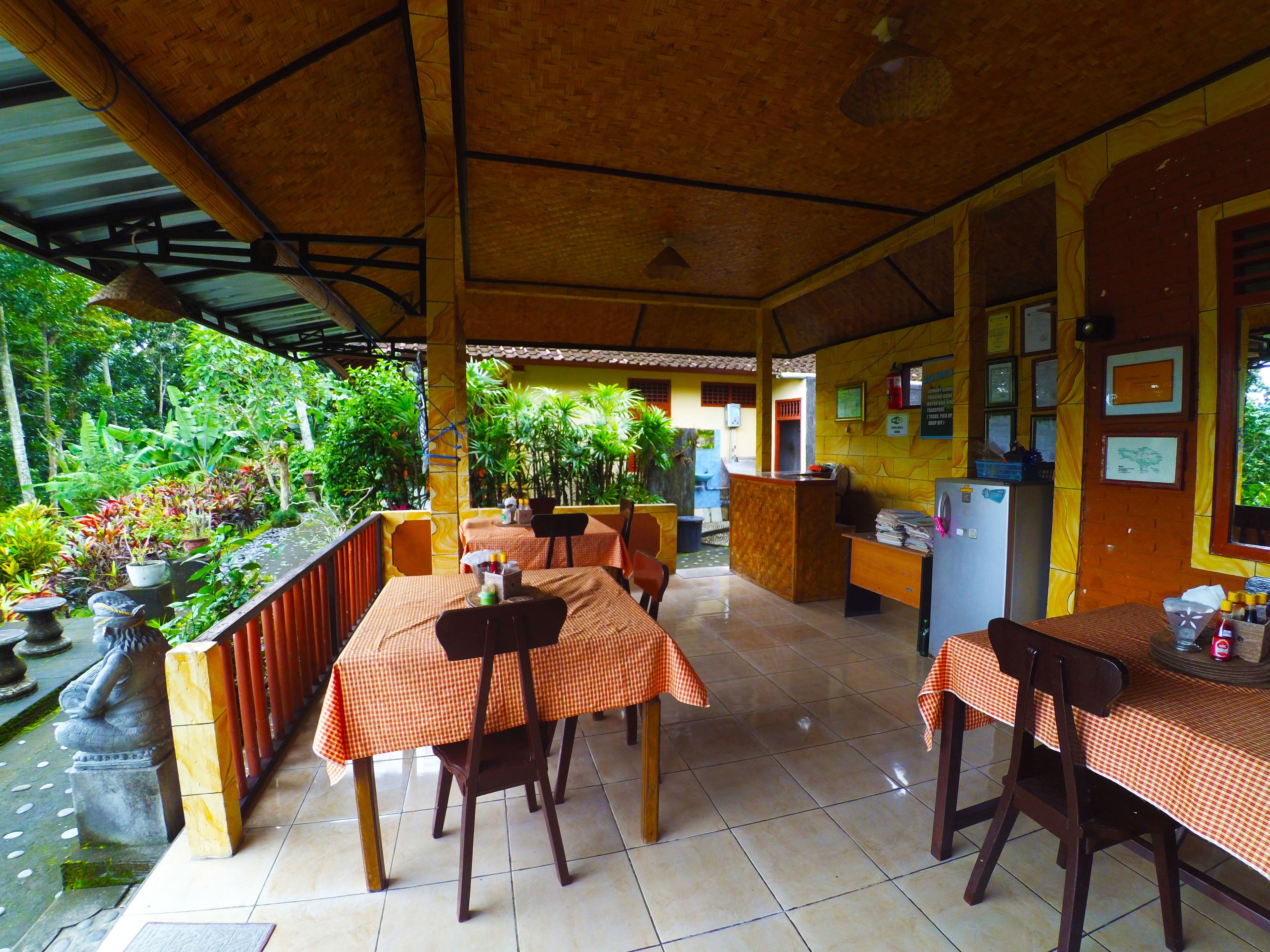 A restaurant with outdoor seating, a reception desk, and various plants.