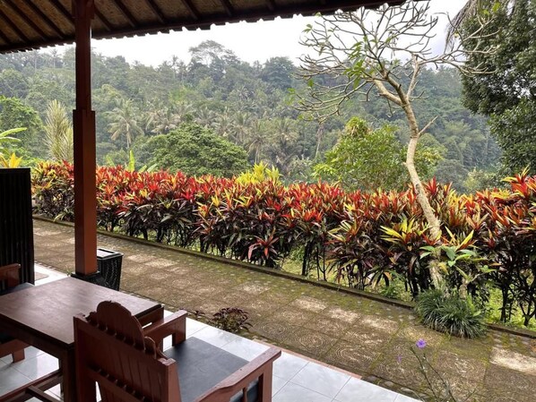 An outdoor seating area with a view of a lush, tropical landscape. - Pondok Batur Indah (Karangasem)