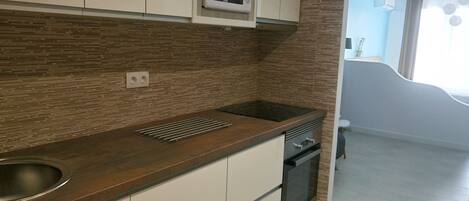 A modern kitchen with a wooden countertop, built-in microwave, and stainless steel appliances.