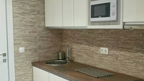 Cozinha moderna com micro-ondas, forno e pia de aço inoxidável.