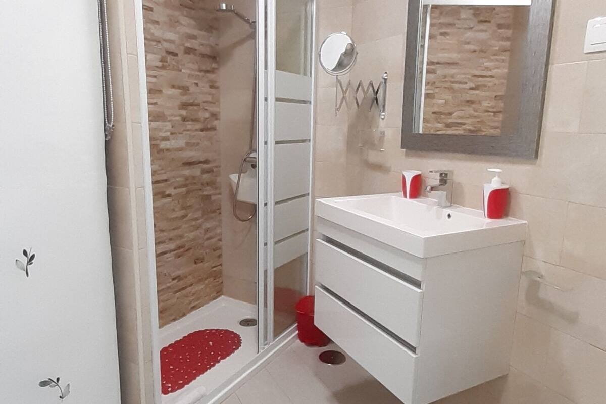 Un baño con ducha, lavabo, inodoro y espejo.