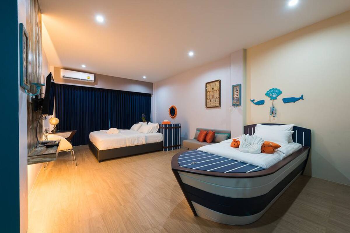 Habitación de hotel con dos camas, un escritorio, una silla y un reloj de pared.