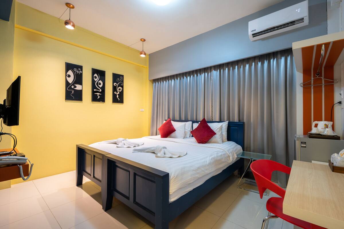 Una habitación de hotel con cama, escritorio, silla y obras de arte en la pared.
