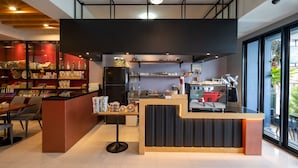A modern coffee shop with a central counter, seating area, and a display of various items.