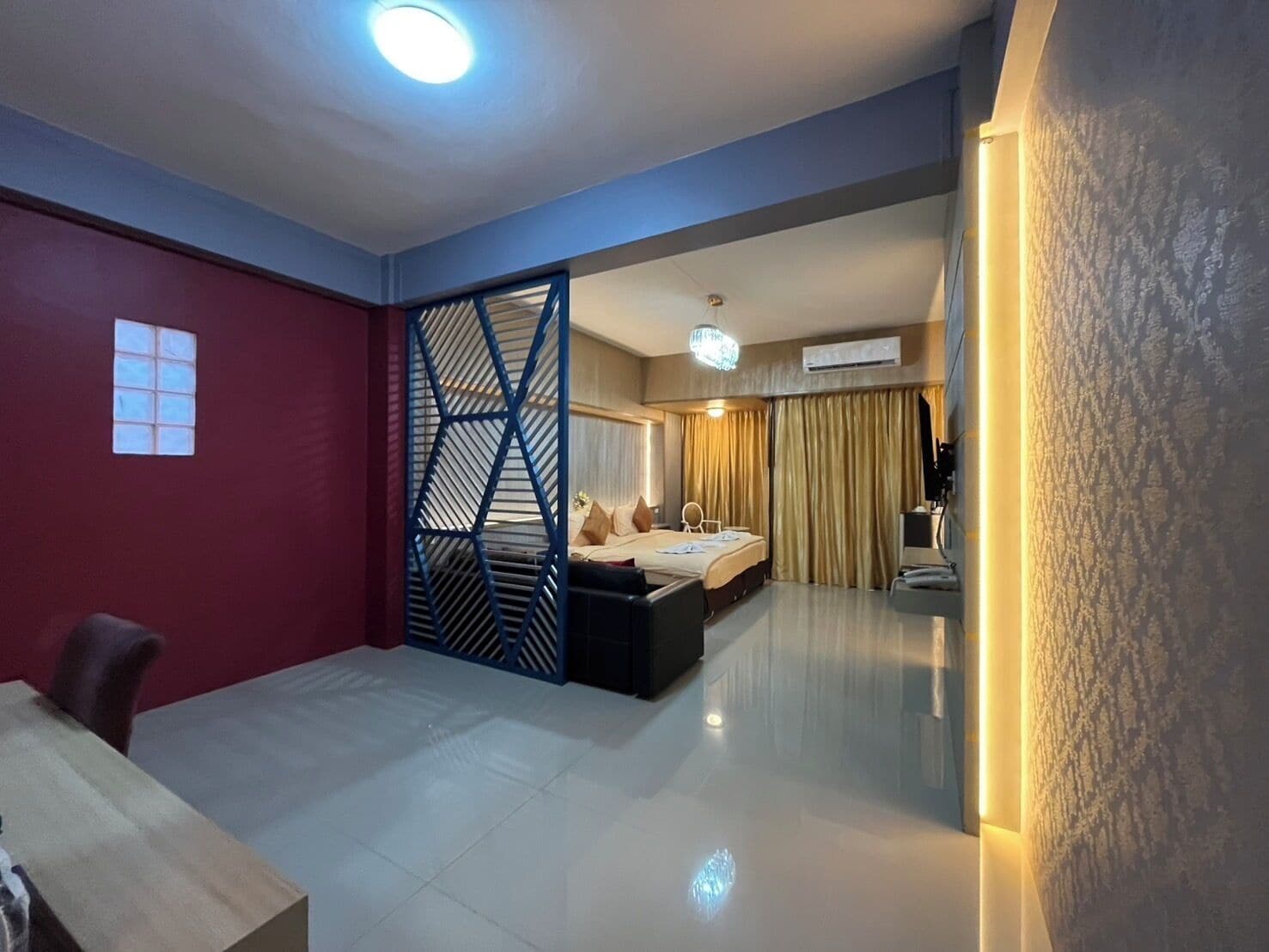 A modern hotel room with a bed, a desk, and a partition.