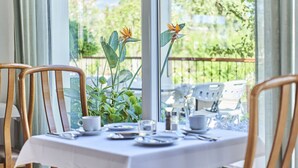 Une table à manger dressée avec des assiettes, des tasses et des couverts, entourée de chaises.