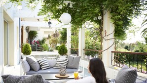 Un balcon avec un canapé, des coussins et une table sur laquelle se trouve une boisson.