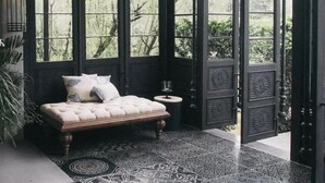 Una habitación con un banco acolchado, una mesita pequeña y una lámpara decorativa.