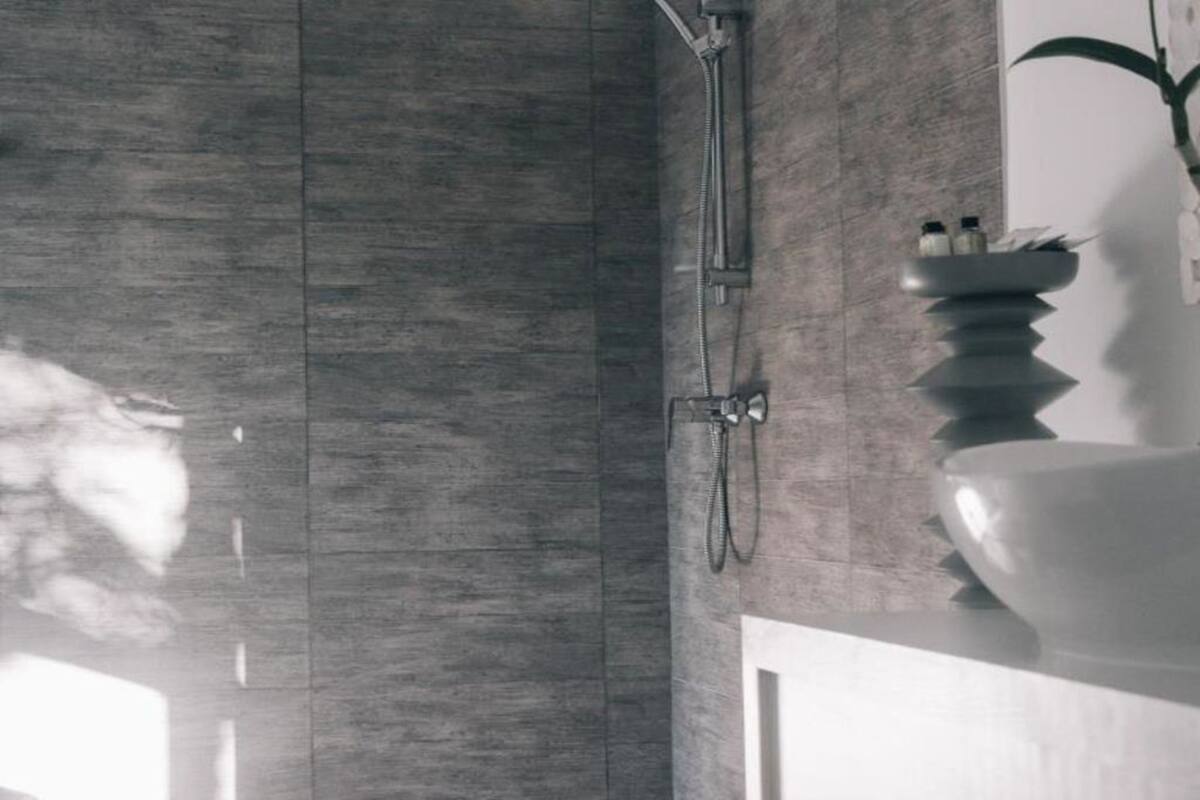 A modern bathroom with a large mirror, a shower, and a sink with a decorative bowl.