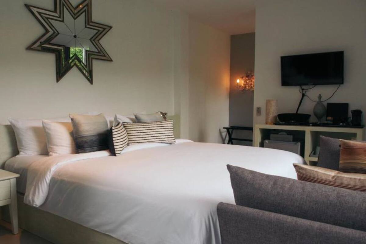 A bedroom with a large bed, a television on the wall, and a desk with a computer.