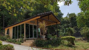 A single-story building with a covered porch, large windows, and a garden with various plants and a small tree. - Samloem Laguna Resort (Koh Rong Sanloem)