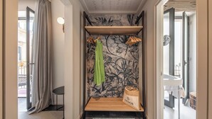 Un baño con ducha, un perchero, un estante de madera y un bolso en la pared.