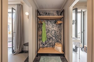 Un baño con ducha, un perchero, un estante de madera y un bolso en la pared.
