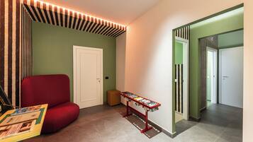 A hallway with a red upholstered chair, a small table with books, and a door with striped wallpaper.