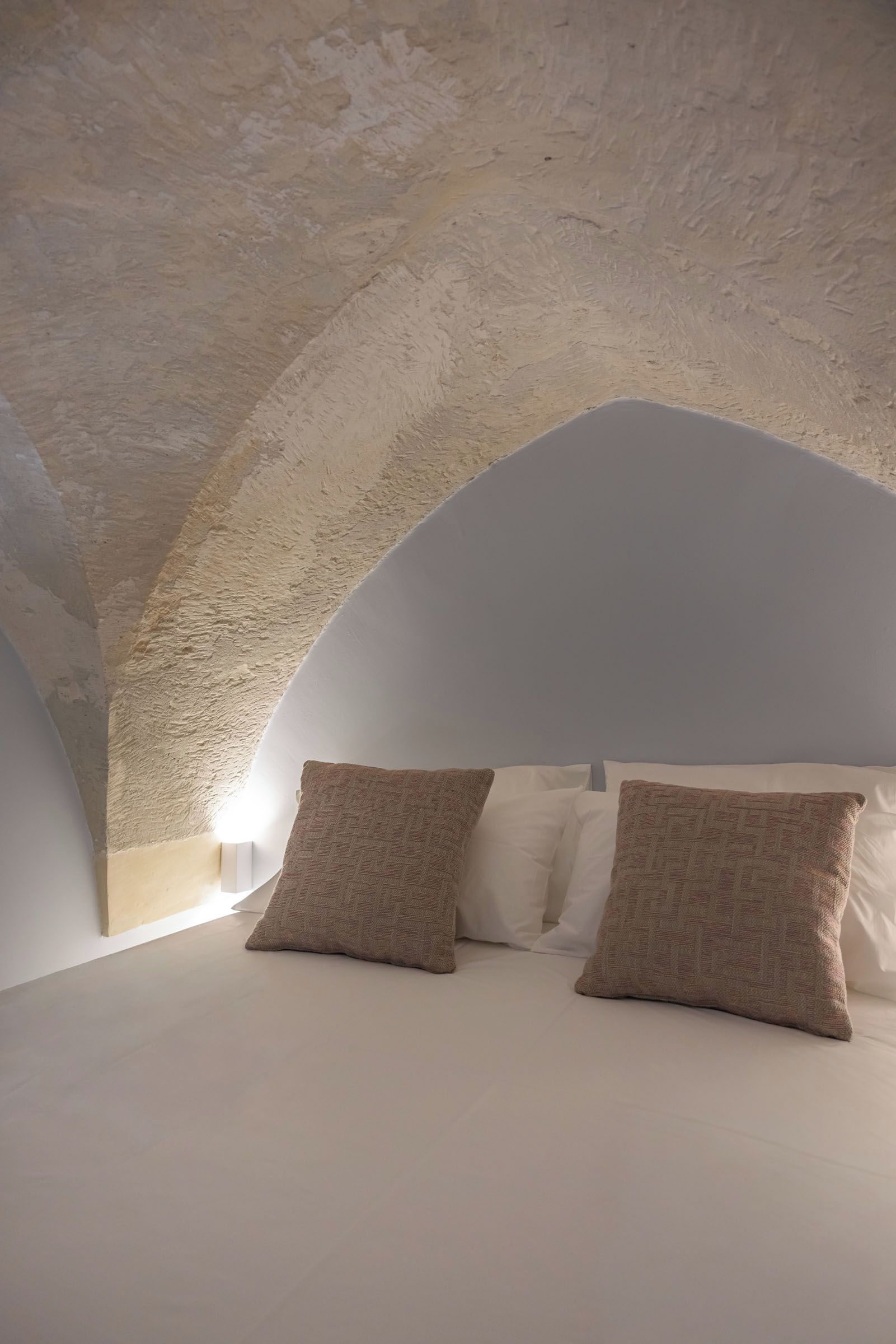 A bedroom with a vaulted ceiling and a bed with two pillows.
