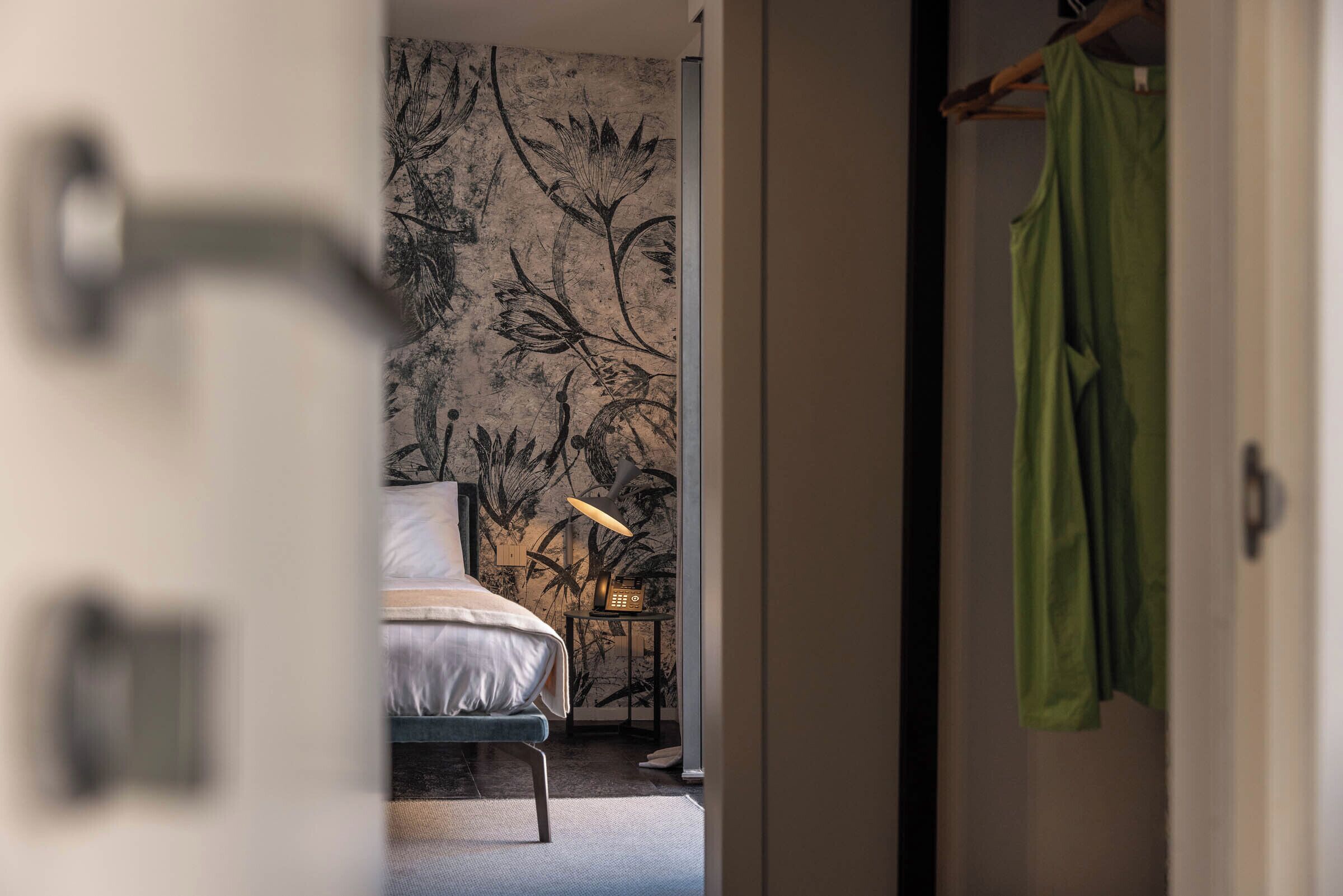 Un dormitorio con cama, mesita de noche y pared con estampado floral.